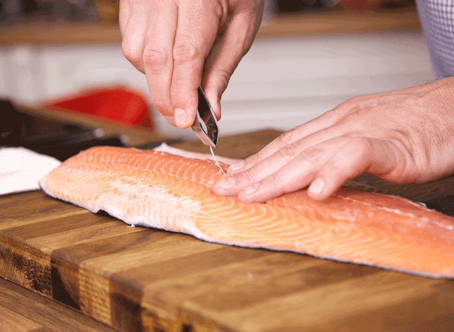 man using tool to debone salmon skin