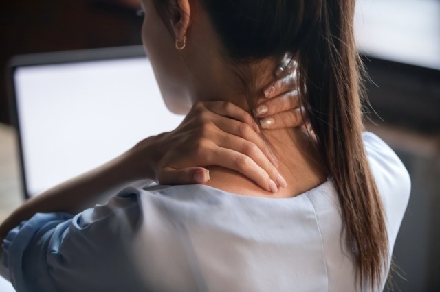 tired woman massaging rubbing stiff sore neck tensed muscles fatigued from computer work in incorrect posture