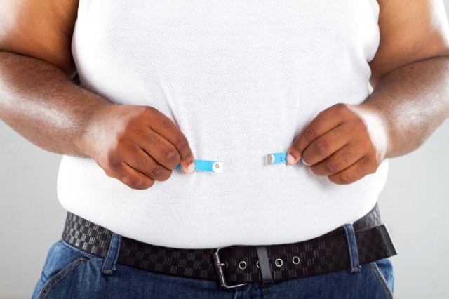 obese man measuring his waist.