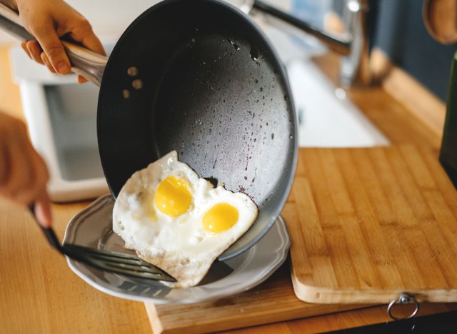 woman plating fried eggs sunny side up