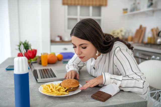 beautiful dark skinned businesswoman with casual hairstyle working on her laptop, looking at screen with concentrated face and touching chin with hand