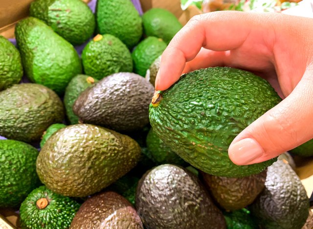 picking an avocado about to check the inside of the stem