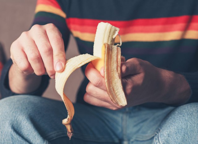 man peeling banana to eat