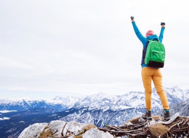 mountain climber cheering at top of mountain