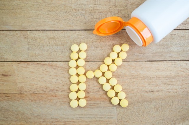 yellow pills forming shape to k alphabet on wood background