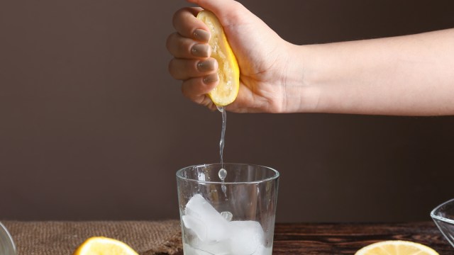 woman squeezing lemon into glass water