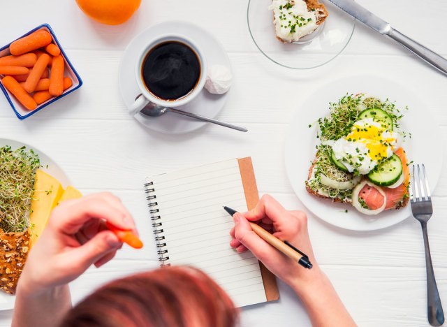 woman writing in food diary with eggnog carrot coffee on the table