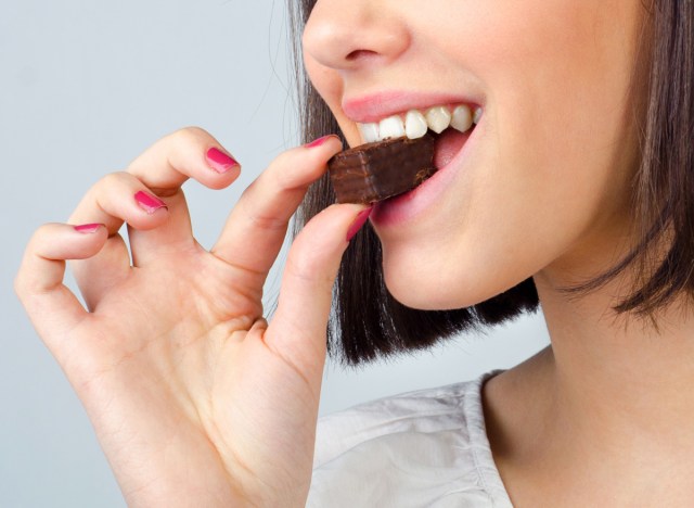 woman taking a piece of chocolate and enjoying her dessert