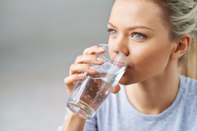 woman drinking water from glass.