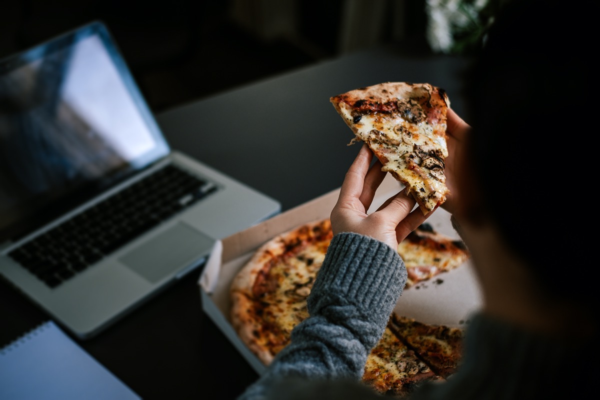 eating pizza and social networking with a laptop.