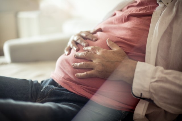 man with hand on his stomach to depict indigestion