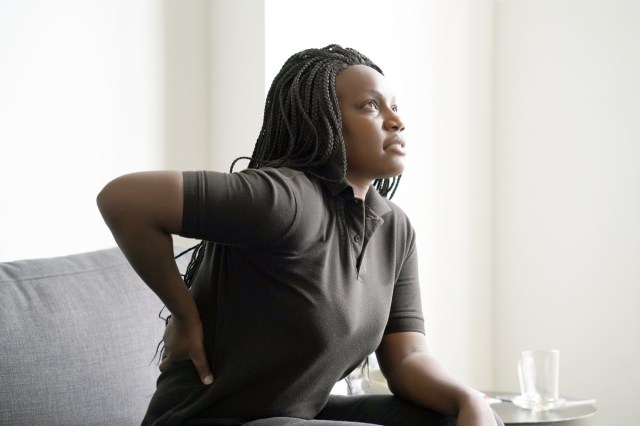 woman with pain in kidneys at home on couch