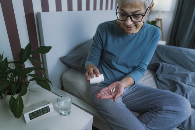 mature woman taking melatonin supplement pill before bed