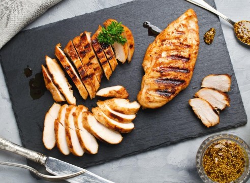 cut up cooked chicken breast on a dark grey cutting board