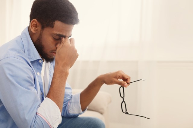 man massaging nose bridge, taking glasses off, having blurry vision or dizziness