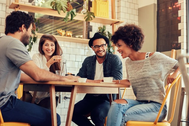 portrait of cheerful young friends having fun while talking in a cafe