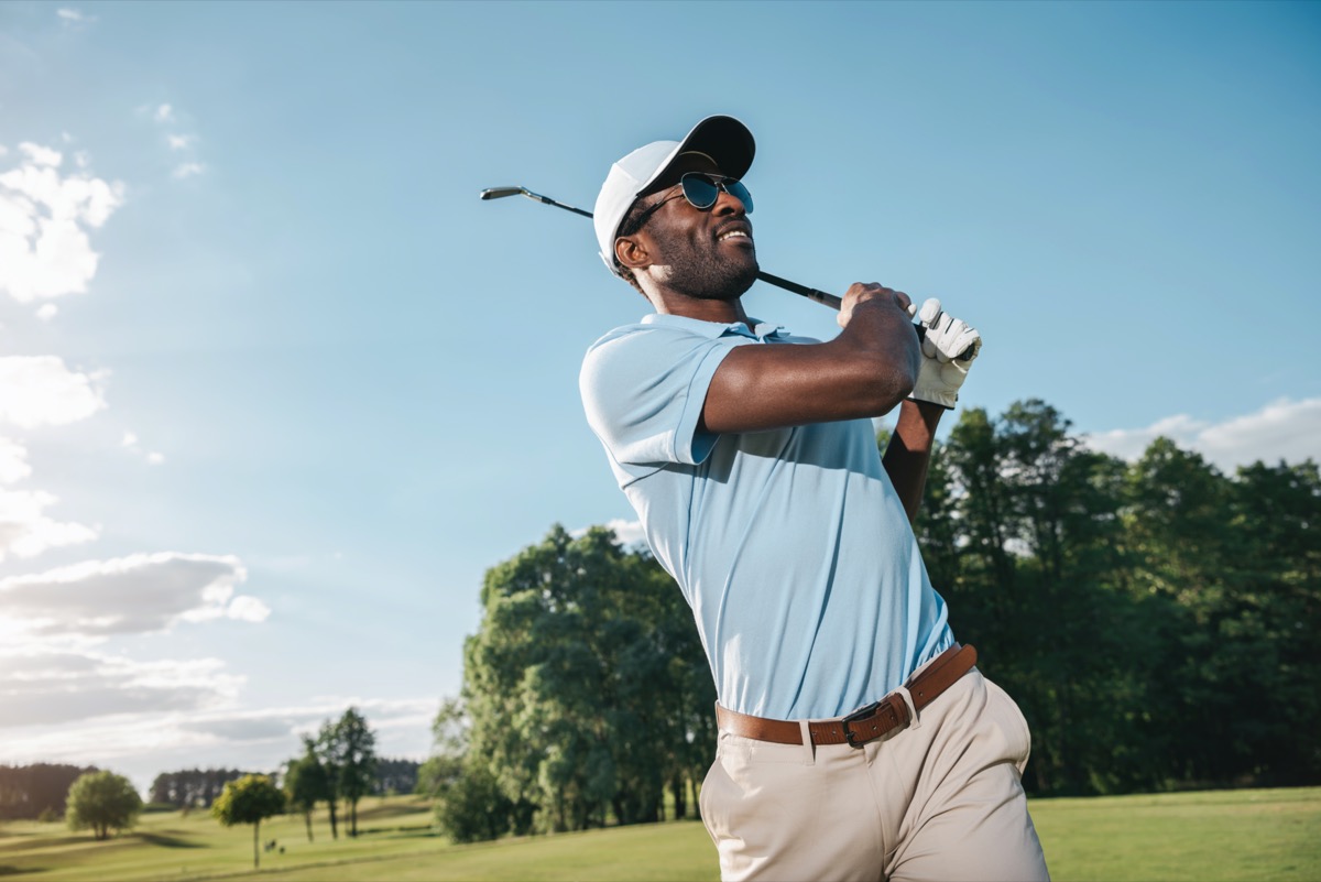 smiling man in cap and sunglasses playing golf