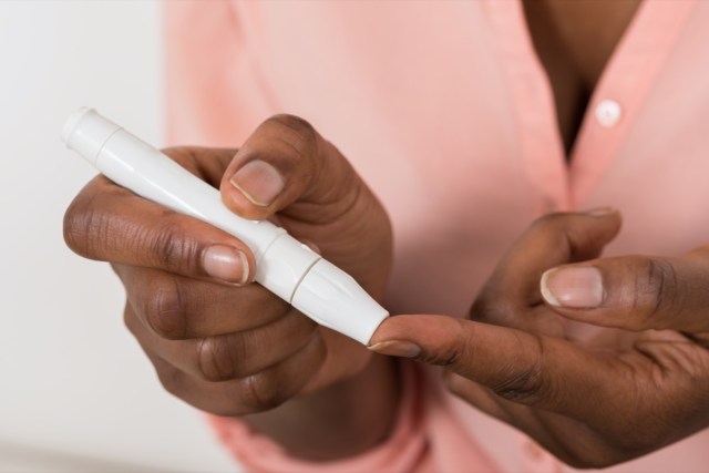 close-up of person's hand checking blood sugar level with glucometer