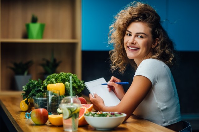 nutritionist working in the office.  doctor writing diet plan on the table and using vegetables.  sports coach