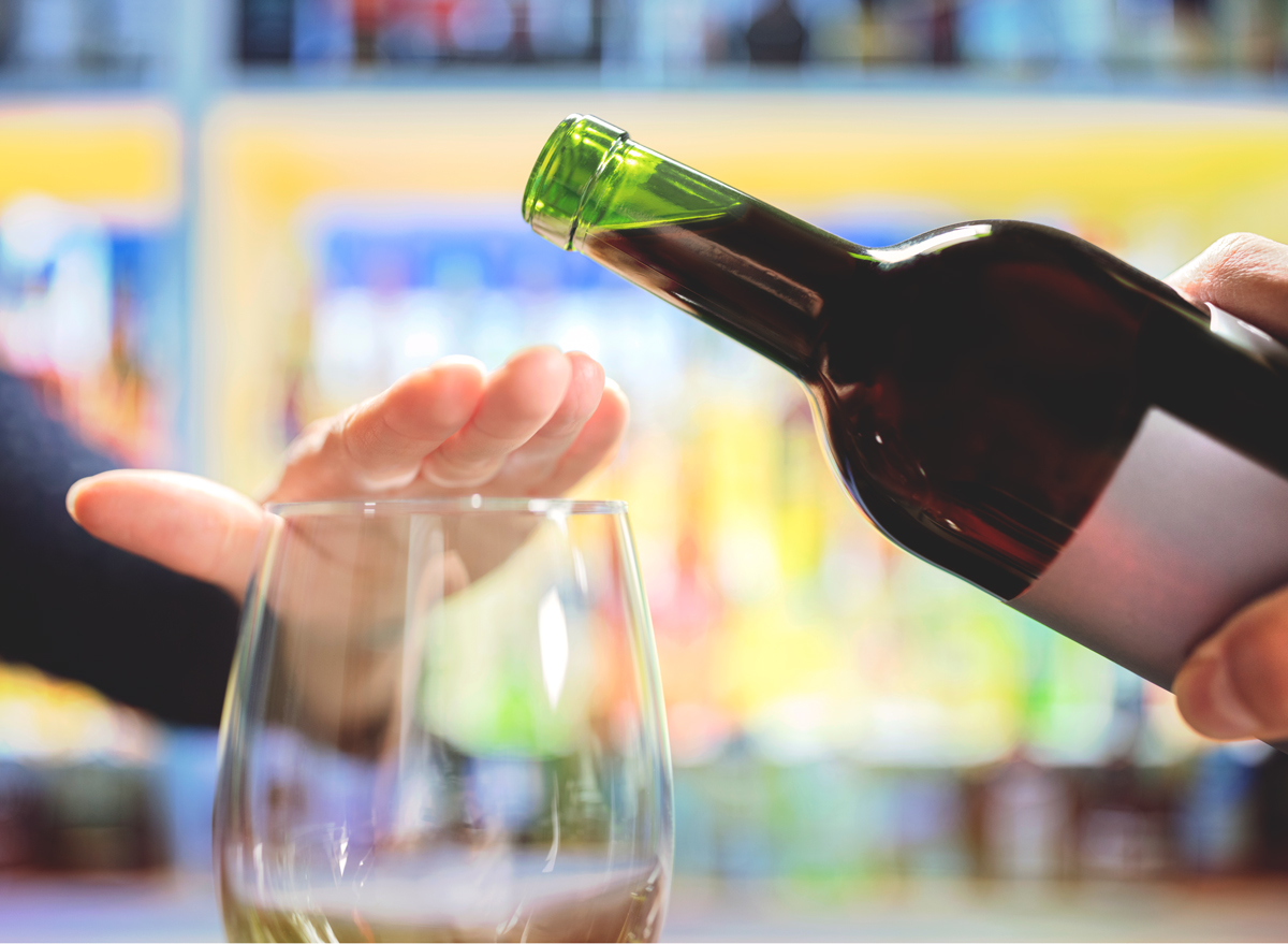 woman refusing or saying no to pouring a glass of wine alcohol