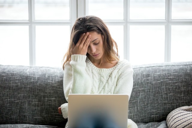 frustrated sad woman feeling tired worried about problems sitting on sofa with laptop, stressed depressed girl bothered to read bad news online, debt email or negative message