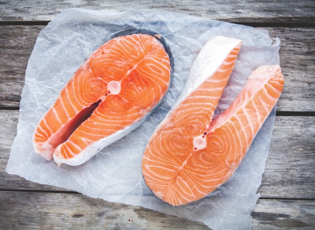 wild vs farmed salmon raw fillets on parchment paper