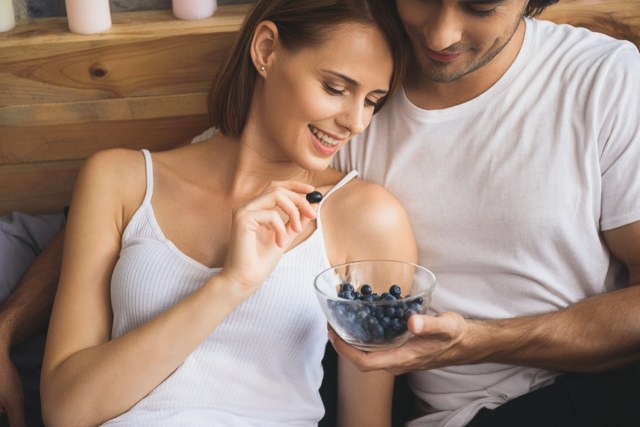 close up of a couple eating blueberries.