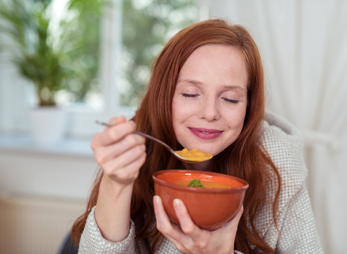 happy woman enjoying her dinner of soup