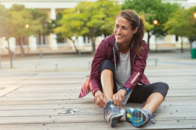 mature fitness woman tie shoelaces on the road