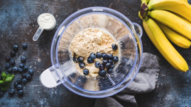 making a smoothie with protein powder blueberries banana in blender
