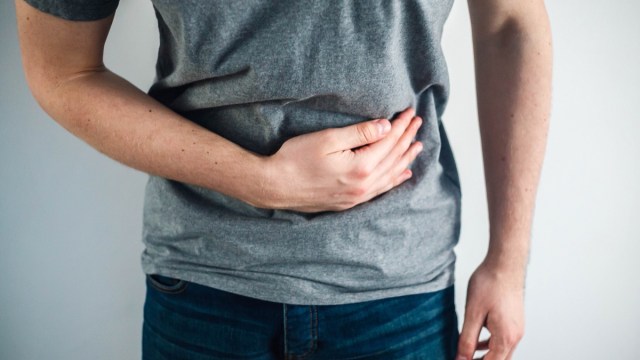 man in gray shirt holding stomach