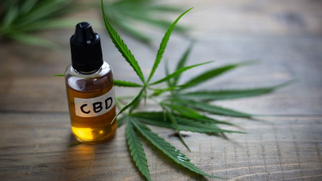 cbd oil bottle next to marijuana leaf