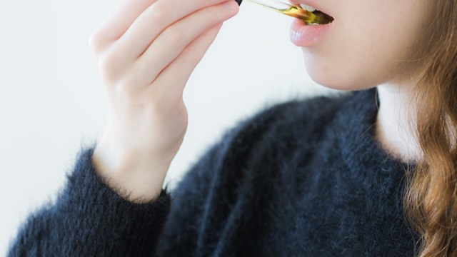 woman taking cbd oil under tongue