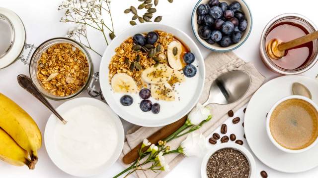 healthy breakfast foods blueberries bananas bowl of yogurt oatmeal and coffee