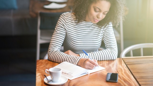 young woman drinking coffee and writing in journal