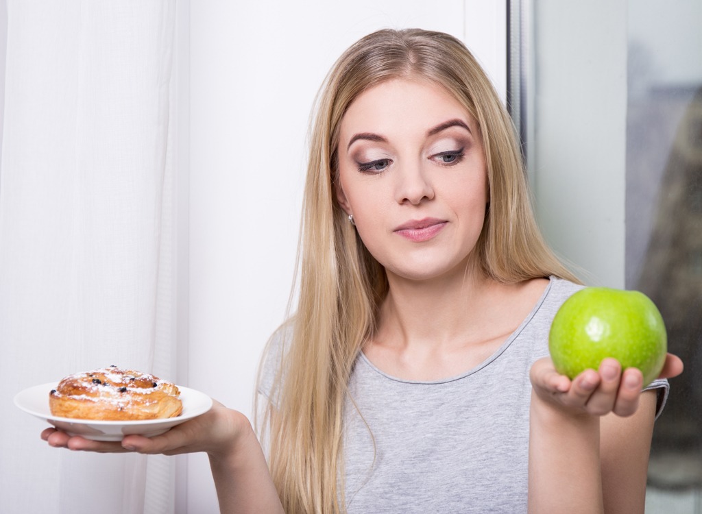 woman choosing apple over sugar-filled pastry