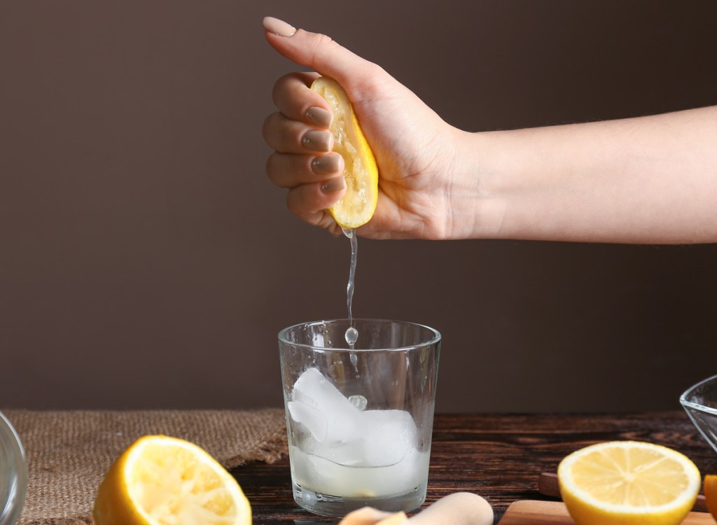 woman squeezing lemon into glass water