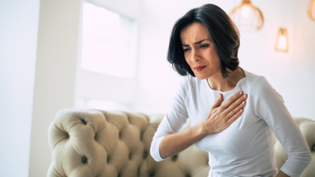 woman who is suffering from a chest pain and touching her heart area