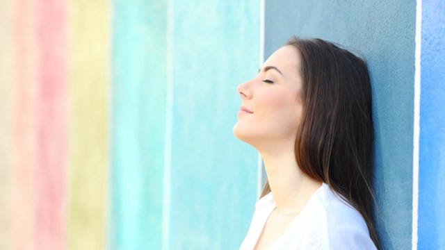 portrait of a relaxed woman resting leaning on a colorful wall on the street