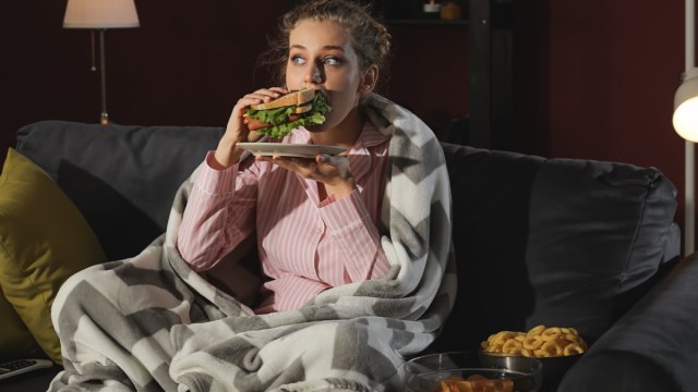 woman eating unhealthy food while watching tv at night.