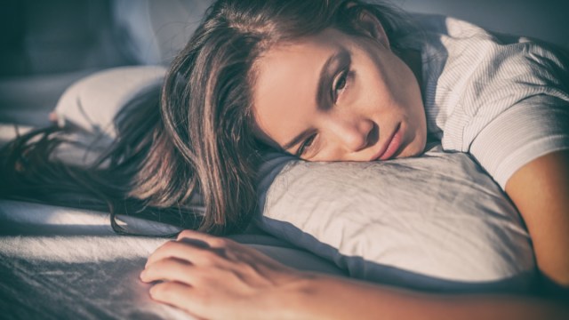 tired woman lying in bed can't sleep late at night with insomnia