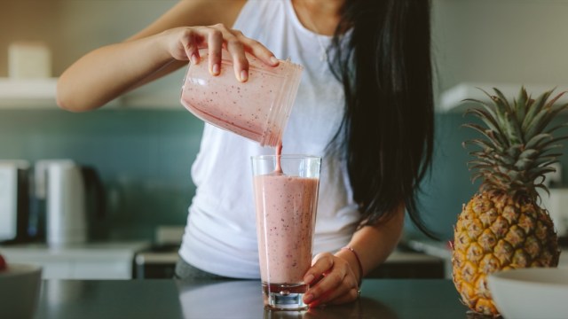 woman pouring smoothie from blender into cup