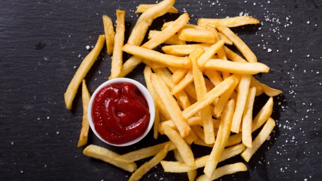 french fries with ketchup on dark background, top view