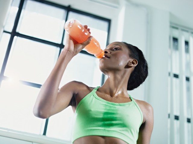 african american woman in sportswear with energy drink in gym