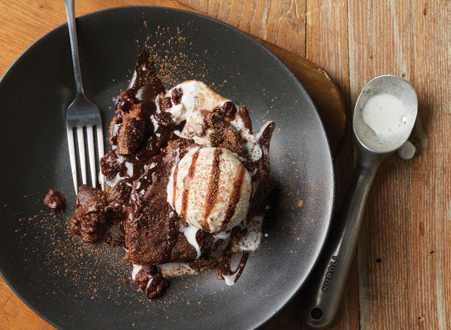 molten lava cherry chocolate cake with frozen yogurt and spoon on black plate