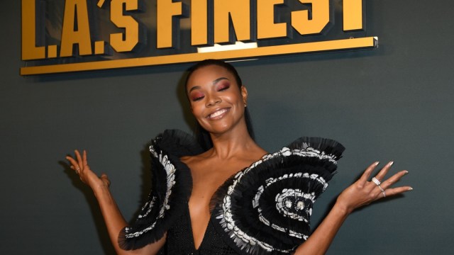 gabrielle union in oversized throw top in front of la finest sign