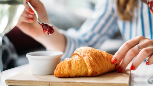 woman eating croissant with jam