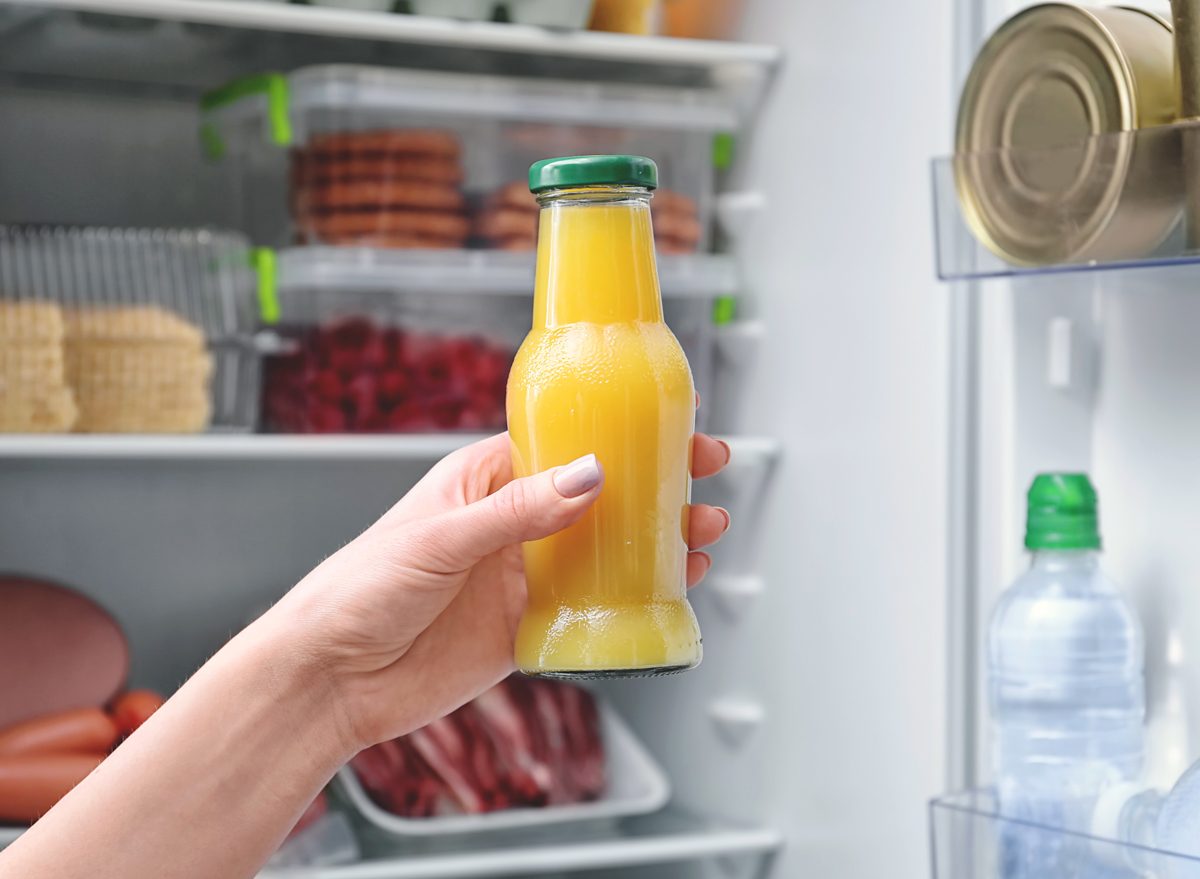 unhealthy orange juice bottle held in front of the refrigerator