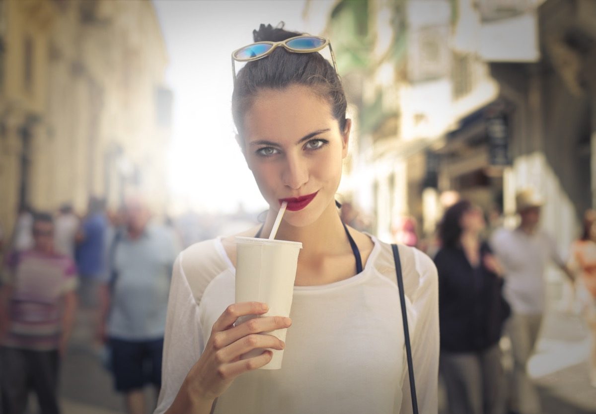 woman drinking from white cup with straw