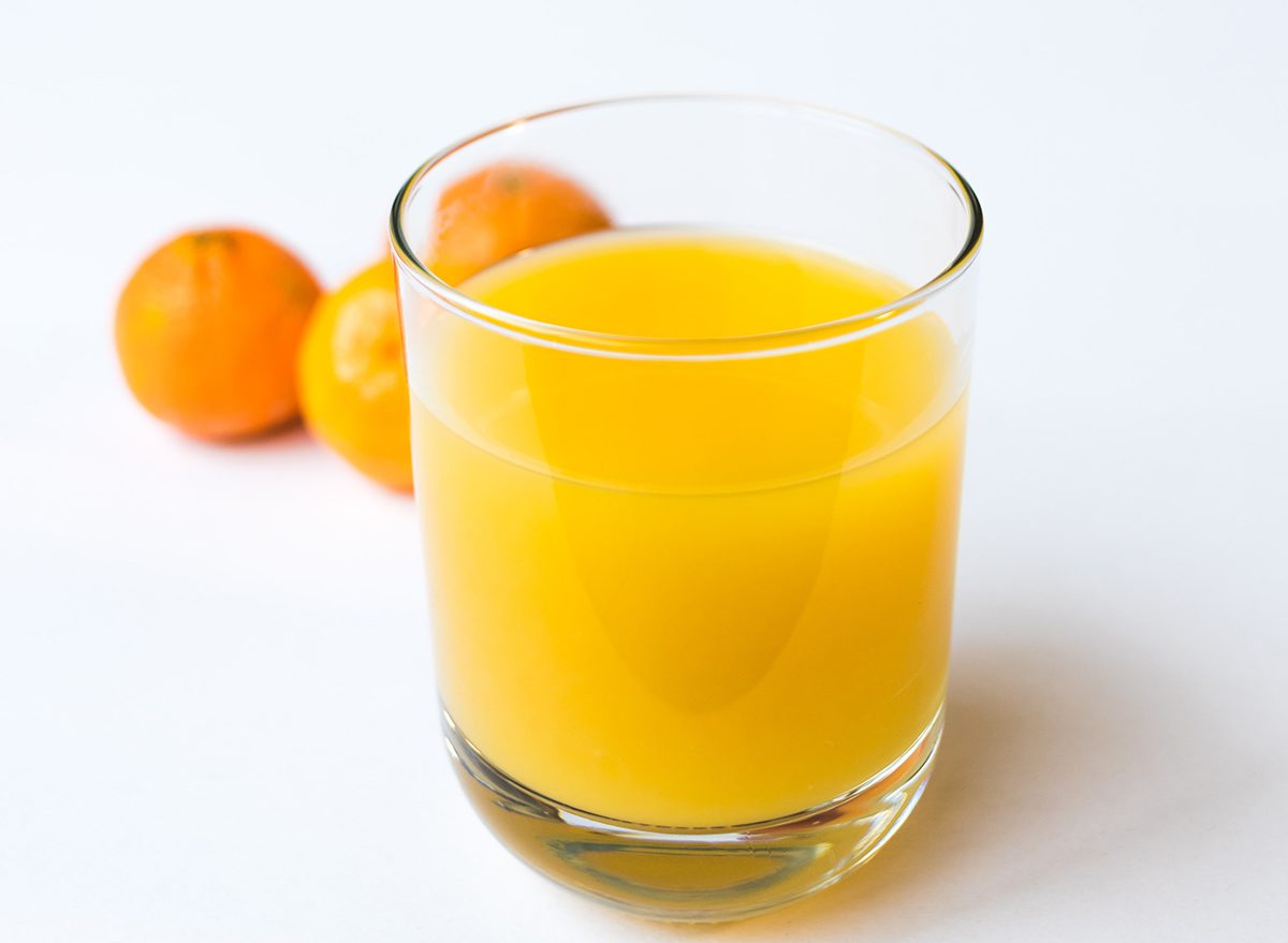 a glass of orange juice with oranges